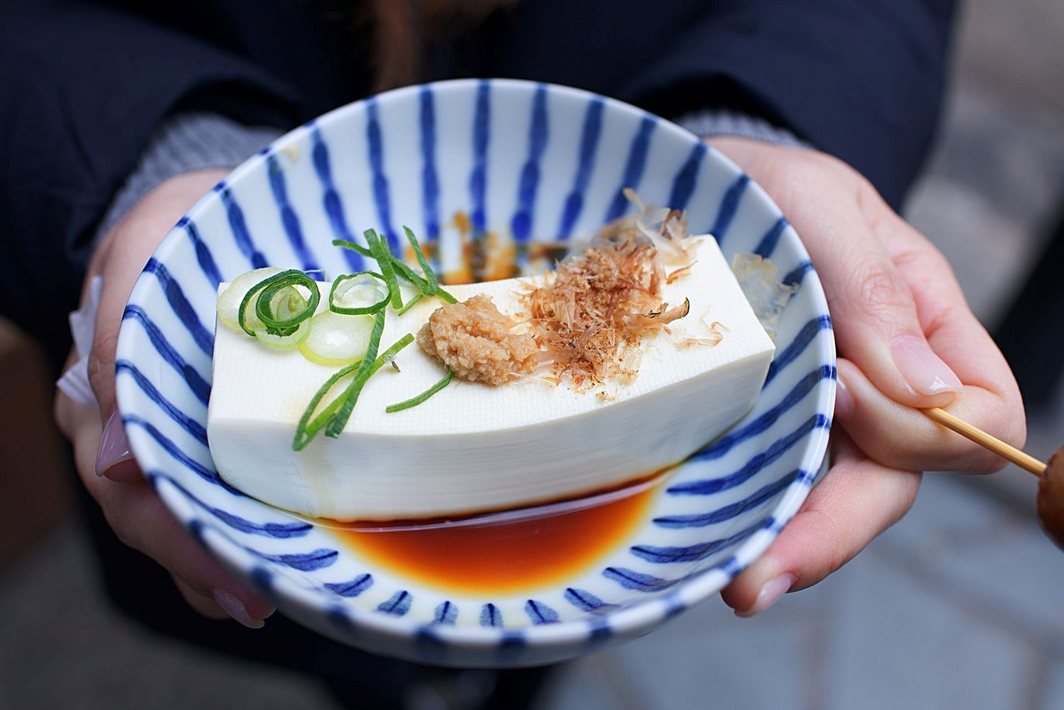 Silken tofu in a bowl with sliced green onions and soy sauce