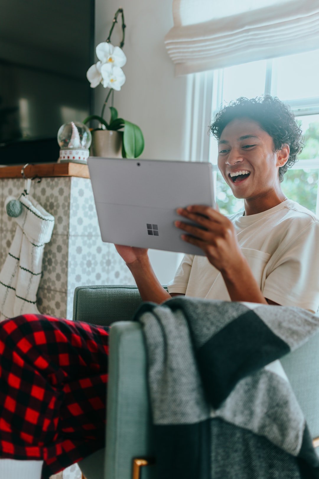 Woman sitting in chair in her pajamas using a tablet and smiling