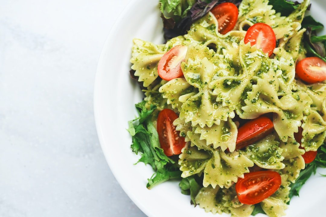 White plate filled with vegan energy foods: pesto pasta